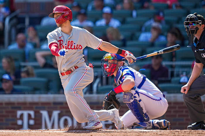 Trea Turner finishes his swing, with his bat behind him and one hand out